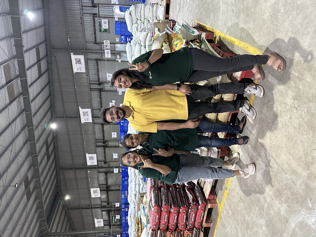 Shahala with three colleagues inside a Jumbotail fulfilment centre, pallets stacked behind them