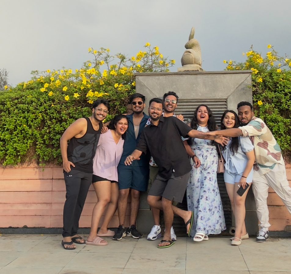 A group with arms around each other in front of a yellow flowering hedge